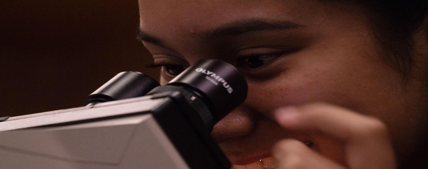 PGCC student smiling while looking into microscope